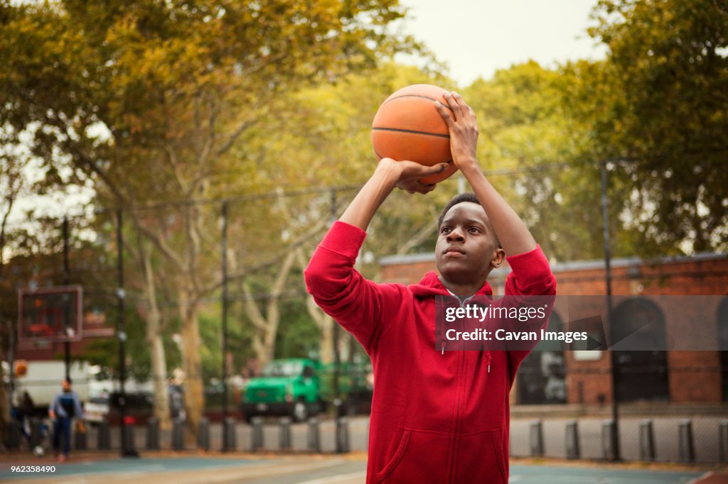 Student taking a shot while playing basketball at court