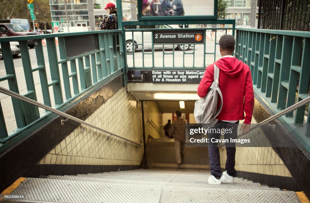 Rear view of student walking down steps in subway