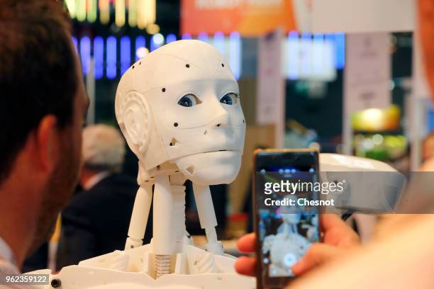 Visitor takes a picture with his smartphone of a humanoid robot made from a 3D printer at the InMoov corner during the Viva Technology show at Parc...