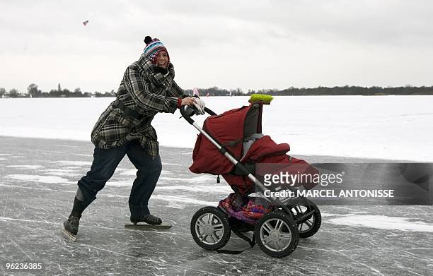 Mother skates as she pushes a baby-carriage on an ice-covered lake in Loosdrecht, The Netherlands, on January 9, 2010. AFP PHOTO / ANP / MARCEL...
