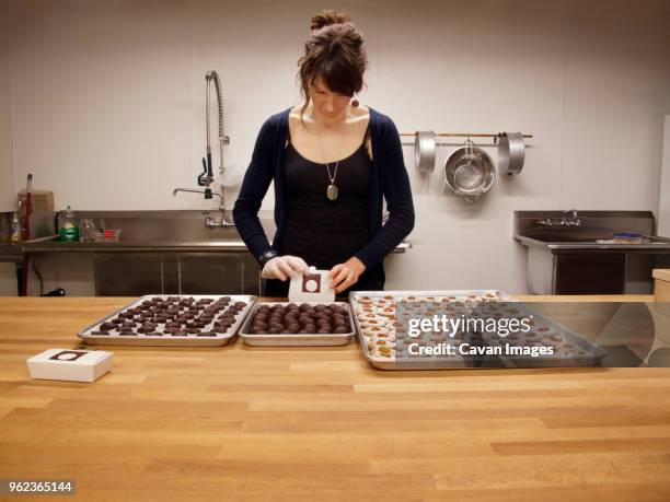 woman packing chocolates and biscuits in box at kitchen counter - chocolate pack stock-fotos und bilder