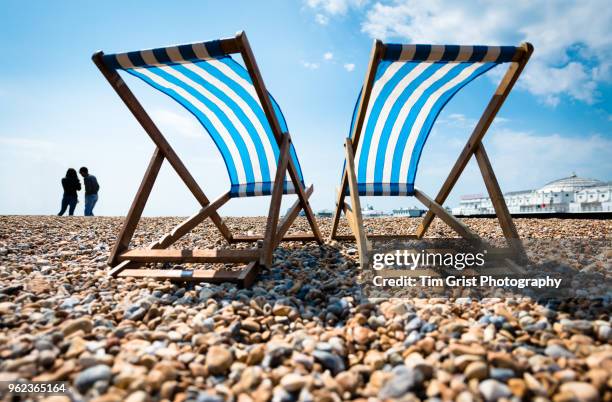 silhouette of young couple and two empty deck chairs and the palace pier, brighton - beach uk stockfoto's en -beelden