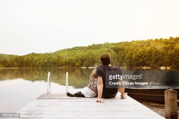 rear view of girl with father sitting on pier - genderblend2015 stock pictures, royalty-free photos & images
