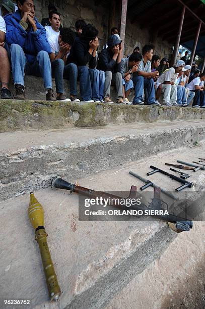 Seized arms including an RPG-7 grenade launcher found in the outskirts of Tegucigalpa during a police operation are displayed next to detainees on...