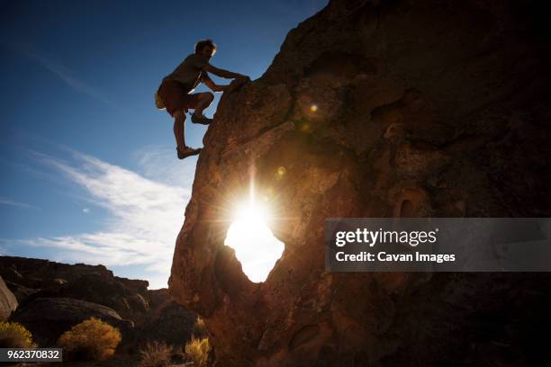 silhouette man climbing rock formation against sky - bishop california stock pictures, royalty-free photos & images