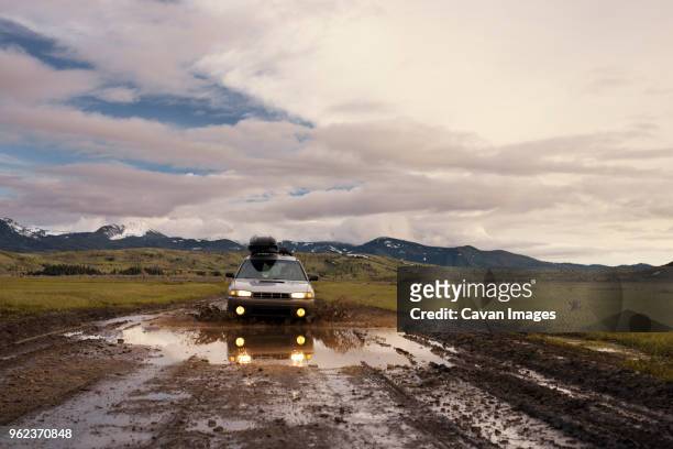 man driving car on dirt road against cloudy sky - car splashing water on people stock pictures, royalty-free photos & images