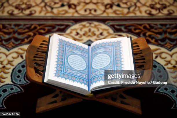 an open holy quran on wood stand. - koran stock pictures, royalty-free photos & images