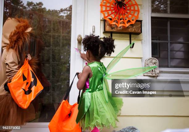 children in halloween costumes standing at doorway during trick or treating - fairy costume stock pictures, royalty-free photos & images