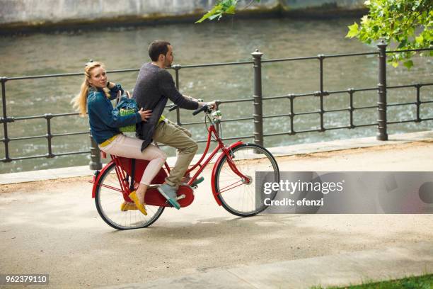 couple riding together bicycle in city - river spree stock pictures, royalty-free photos & images