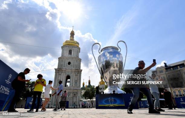 People make selfies with a huge trophy set in the Ukrainian capital of Kiev on May 25 a day before of the 2018 UEFA Champions League Cup final...