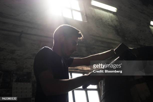 Cooper uses a mallet while rounding off a wine barrel during manufacture ahead of the grape harvest season and port production at the...