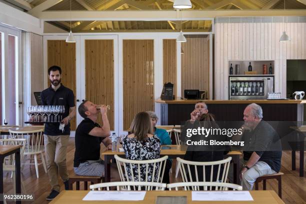 Visitors drink samples of Port while in a bar at the Quinta do Bomfim vineyards in the Douro Valley grape growing region in Alijo, Portugal, on...