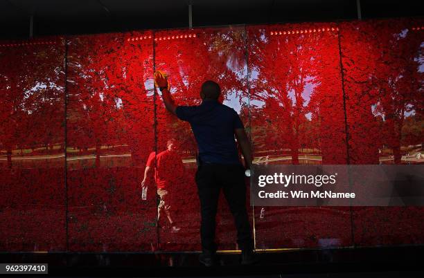 Romel Martin cleans glass panels while assisting with the installation of a temporary pop-up "Poppy Memorial" on the national mall near the Lincoln...