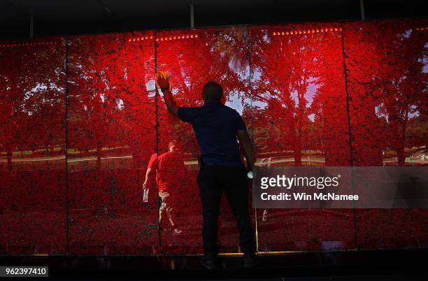 Romel Martin cleans glass panels while assisting with the installation of a temporary pop-up "Poppy Memorial" on the national mall near the Lincoln...