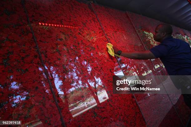 Romel Martin cleans glass panels while assisting with the installation of a temporary pop-up "Poppy Memorial" on the national mall near the Lincoln...