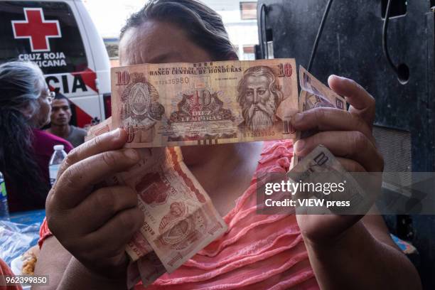 Woman shows a Honduran bank note, while the migrant caravan rest in a shelter on their way through Mexicali to Tijuana and then apply for asylum in...