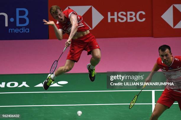 Kim Astrup of Denmark hits a return against Yuki Kaneko and Takuto Inoue of Japan as his teammate Anders Skaarup Rasmussen looks on during their...