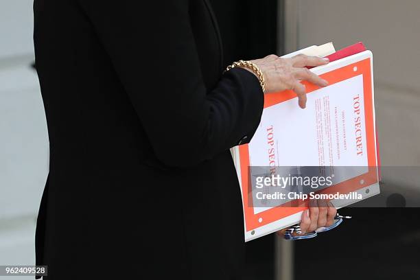 White House employee holds a notebook with 'Top Secret' markings while waiting for U.S. President Donald Trump to depart the White House May 25, 2018...