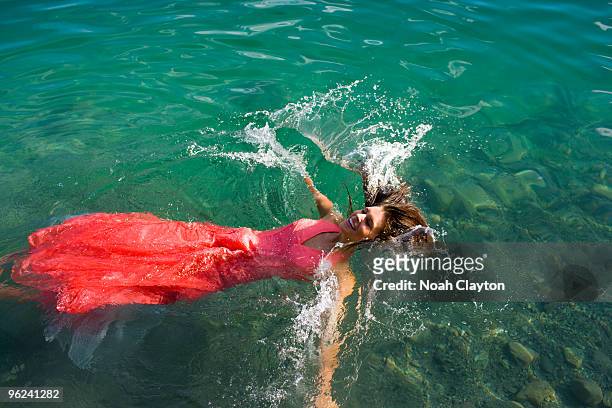smiling young woman falling into lake - girls in wet dresses stock-fotos und bilder