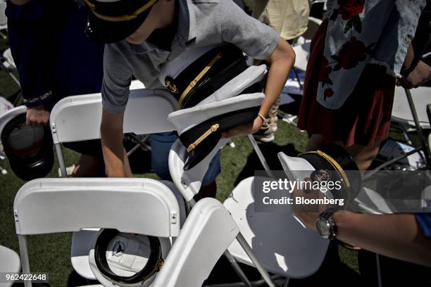 Children pick up caps that were thrown in the air by graduating midshipmen during the United States Naval Academy graduation and commissioning...