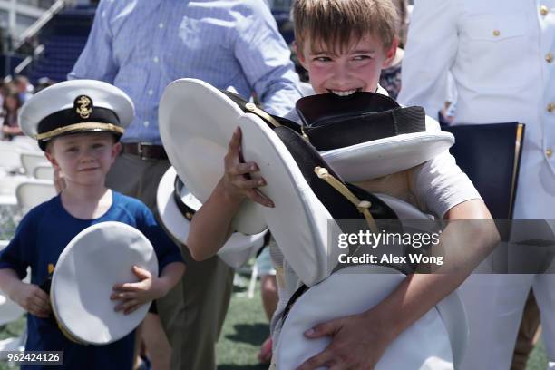 Children collect caps after they were tossed by graduates during a graduation ceremony at the Navy-Marine Corps Memorial Stadium of the U.S. Naval...