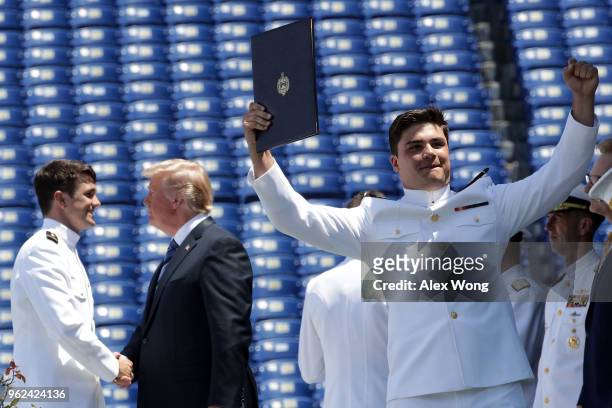 Navy graduate celebrates after he received his diploma as U.S. President shakes hands with another graduate during a graduation ceremony at the...