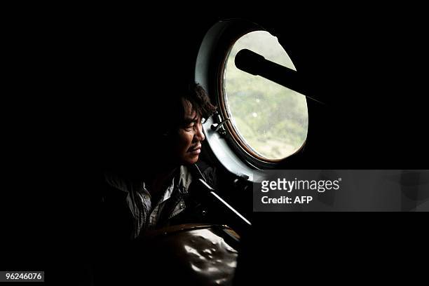 Foreing tourist looks through the porthole of the Mi-8 military helicopter aboard which he is being evacuated from the village of Aguas Calientes,...
