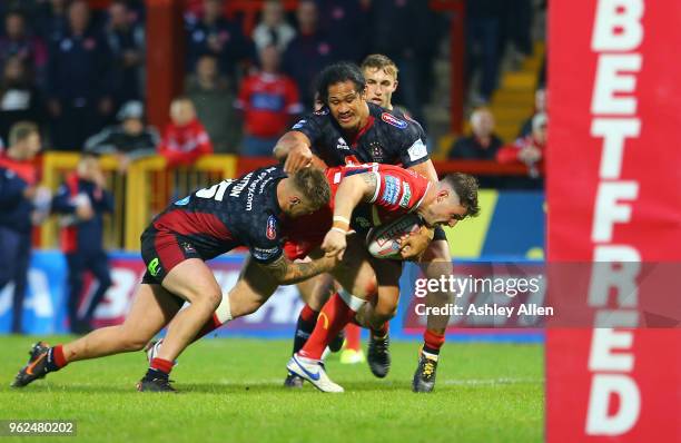 Ben Kavanagh of Hull KR is slowed down by Ryan Sutton and Taulima Tautai of Wigan Warriors during the Betfred Super League at KCOM Craven Park on May...