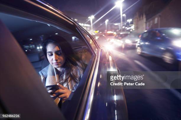 woman on phone in back of car at night - rue 21 photos et images de collection