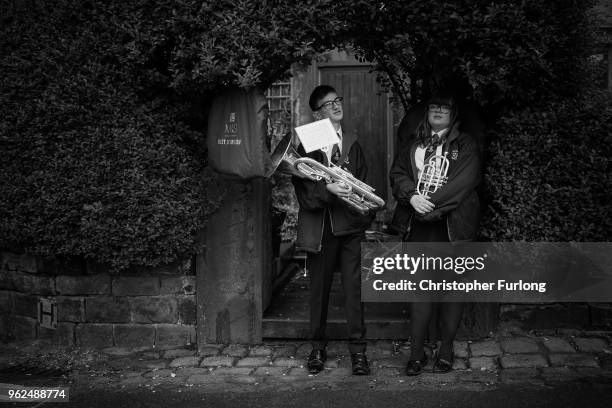 Members of the Dobcross Youth Band shelter from the rain as they prepare to compete in the Whit Friday brass band competition, in the village of...