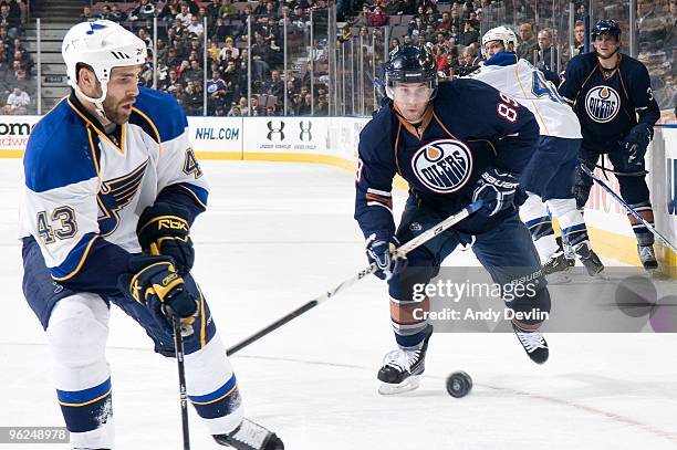 Mike Weaver of the St. Louis Blues tries to control the flying puck while Sam Gagner of the Edmonton Oilers defends at Rexall Place on January 28,...
