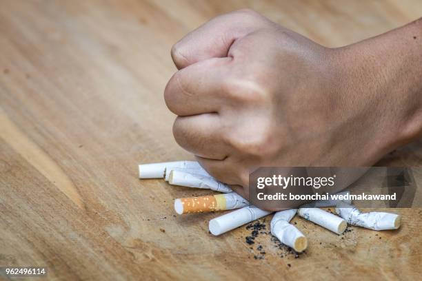 male hand destroying cigarettes - stop smoking concept - stoppen met roken stockfoto's en -beelden