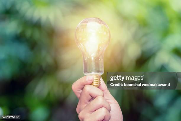 closeup hand holding light bulb while using on laptop, new ideas and creativity concept. - 覚悟 ストックフォトと画像