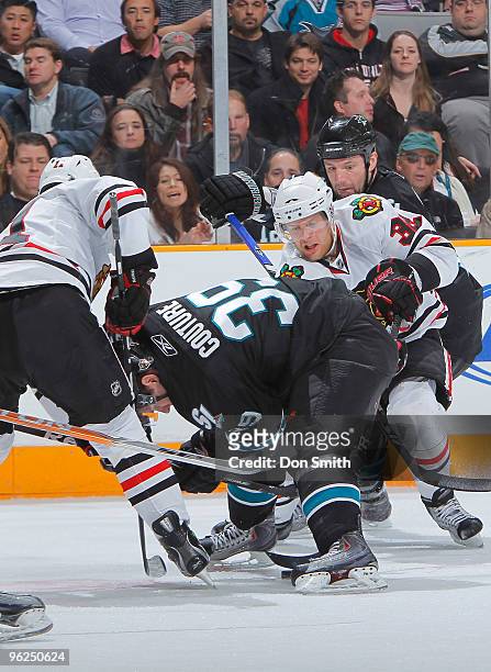 John Madden and Kris Versteeg of the Chicago Blackhawks try to poke the puck out from under Logan Couture of the San Jose Sharks during an NHL game...
