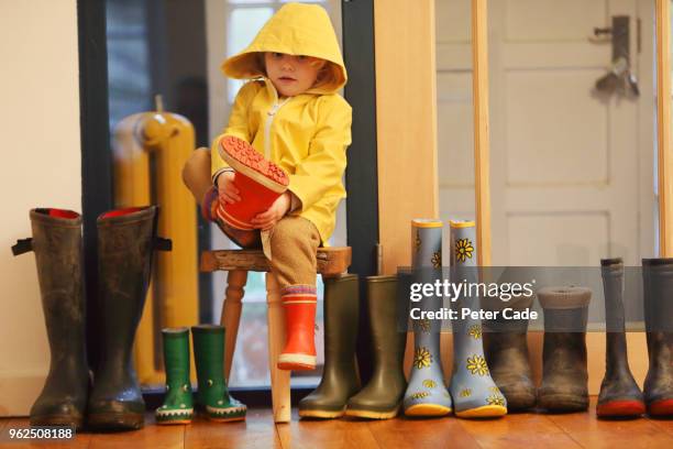 young child putting on wellington boots - blocking stock pictures, royalty-free photos & images