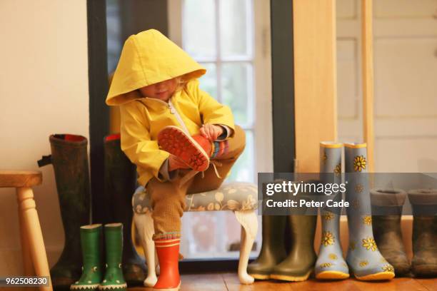 young child putting on wellington boots - girls shoes stock-fotos und bilder