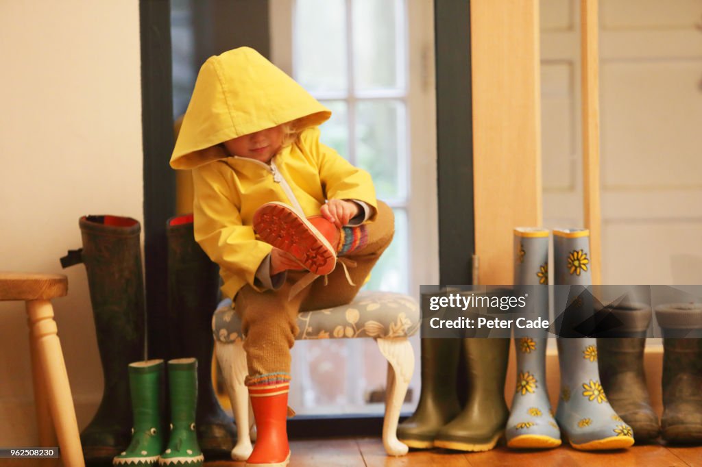 Young child putting on wellington boots