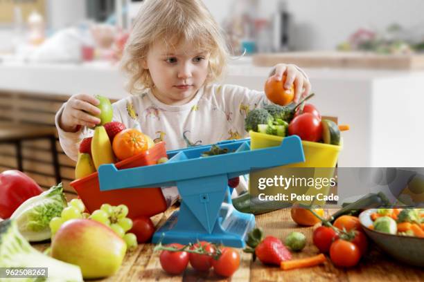 young child weighing fruit and vegetables in scales - 5 am tag stock-fotos und bilder