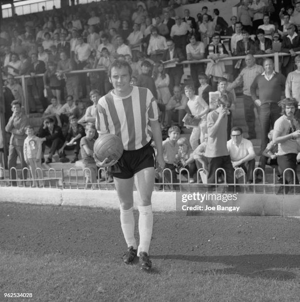 Scottish professional footballer and captiain of Brentford FC, Bobby Ross pictured holding a ball on the pitch at Brentford's Griffin Park stadium in...