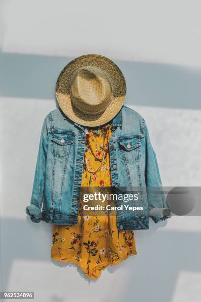 denim jacket and floral summer yellow dress with sunhat - white hat fashion item stock-fotos und bilder