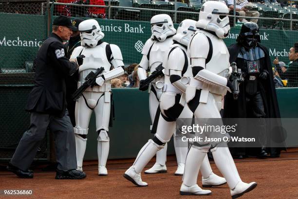 Umpire Jim Wolf is escorted onto the field by Star Wars Stormtroopers on Star Wars Night before the game between the Oakland Athletics and the...