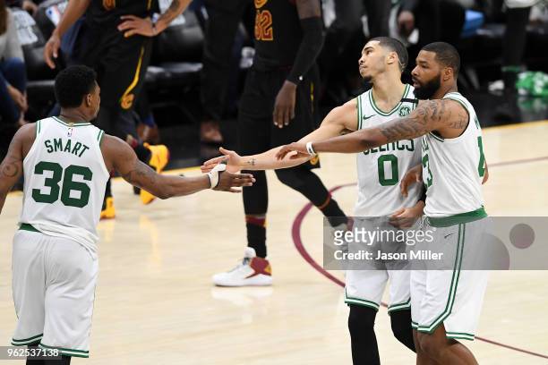 Marcus Smart, Jayson Tatum and Marcus Morris of the Boston Celtics react after a play in the third quarter against the Cleveland Cavaliers during...