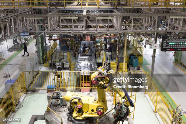 Robotic arm prepares to lift a windshield for a Mahindra & Mahindra Ltd. TUV 300 sport-utility vehicle on the production line at the company's...