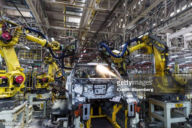 Robotic arms assemble a Mahindra & Mahindra Ltd. XUV 500 sport-utility vehicle on the production line at the company's facility in Chakan,...