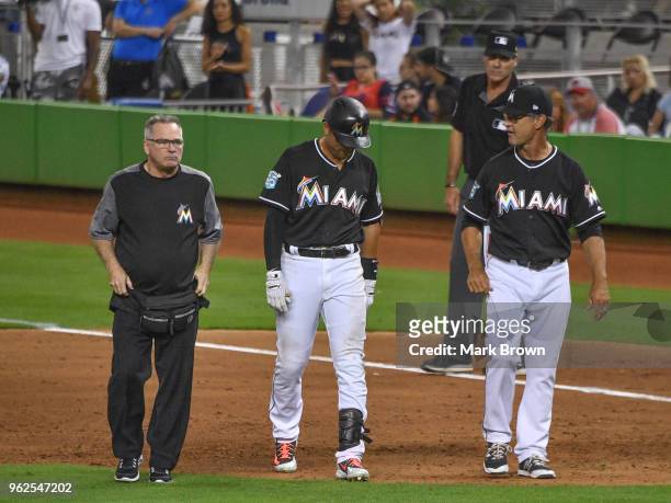 Martin Prado of the Miami Marlins leaves the game with Don Mattingly and trainer Mike Kozak after getting injured running to first base during the...