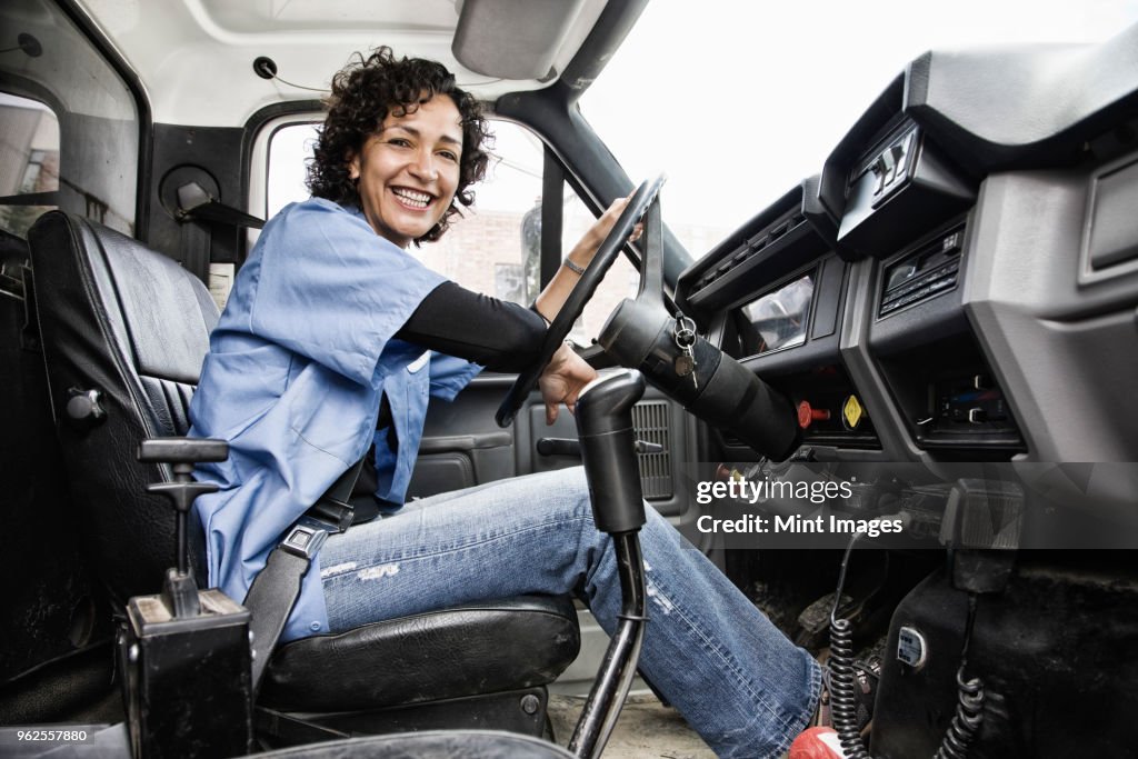 Hispanic woman truck driver and company delivery truck.
