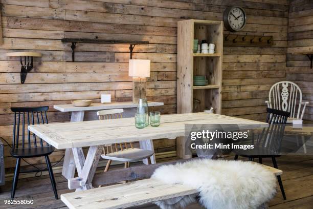 display of furniture made from recycled wood, including dining table and bench, bookshelf and chair, wooden floor and wall. - sheepskin stock pictures, royalty-free photos & images