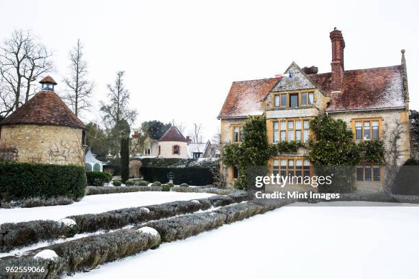 historic 17th century manor house with tall chimneys, a hotel with snow covered grounds in winter. - south east england 個照片及圖片檔