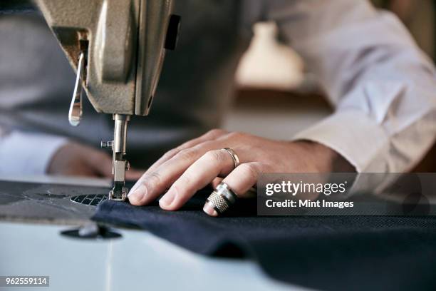 man using an industrial sewing machine, stitching a garment. - thimble stock pictures, royalty-free photos & images