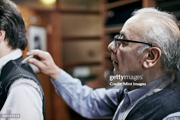tailor fitting a jacket on a customer using tailors chalk to mark the fabric. - tailoring chalk stock pictures, royalty-free photos & images